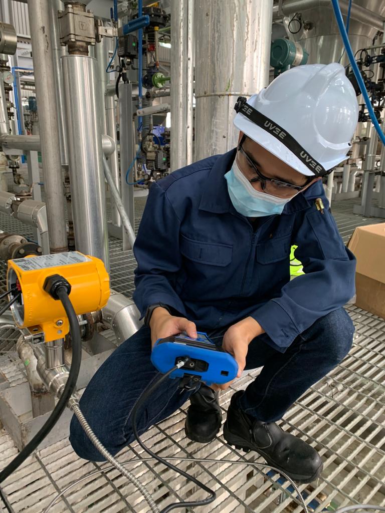 PIC engineer checking a flow transmitter on site with a handheld communicator